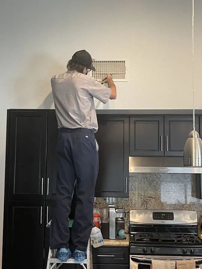 Technician inspecting an air vent during HVAC service in South Lebanon